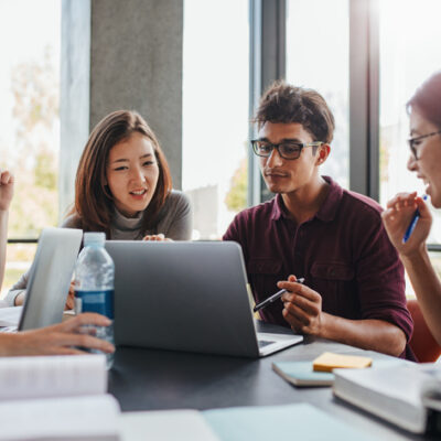 Multiracial young people doing group study at table. University students sitting together at table with books and laptop for researching information for their project.